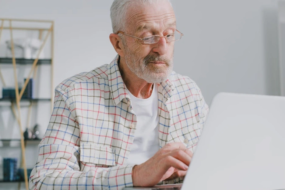 Dizüstü bilgisayarında online ders çalışan ve not alan bir kişi